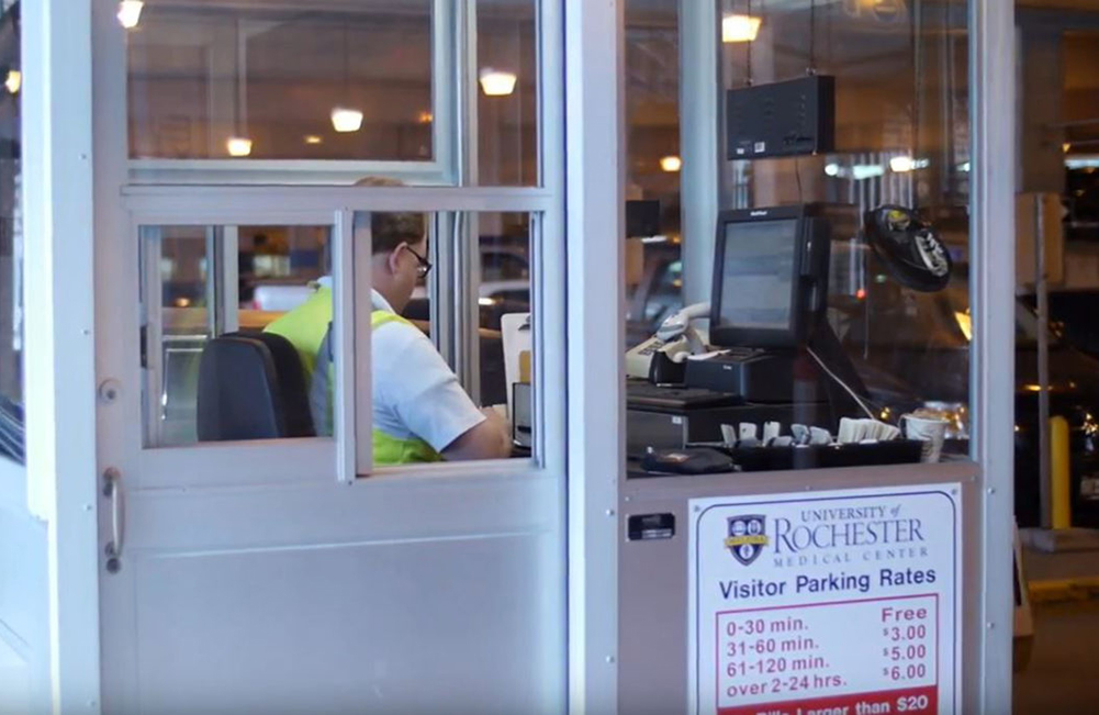 Parking employee sitting at toll booth in garage.