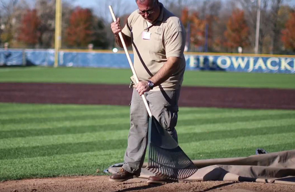 grounds worker raking the infield at Towers Field.