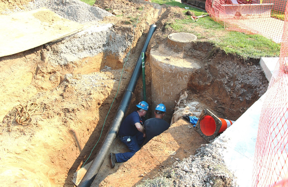 Utilities workers performing underground maintenance on piping.