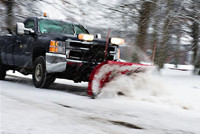 snow plow truck on snowy road on campus.